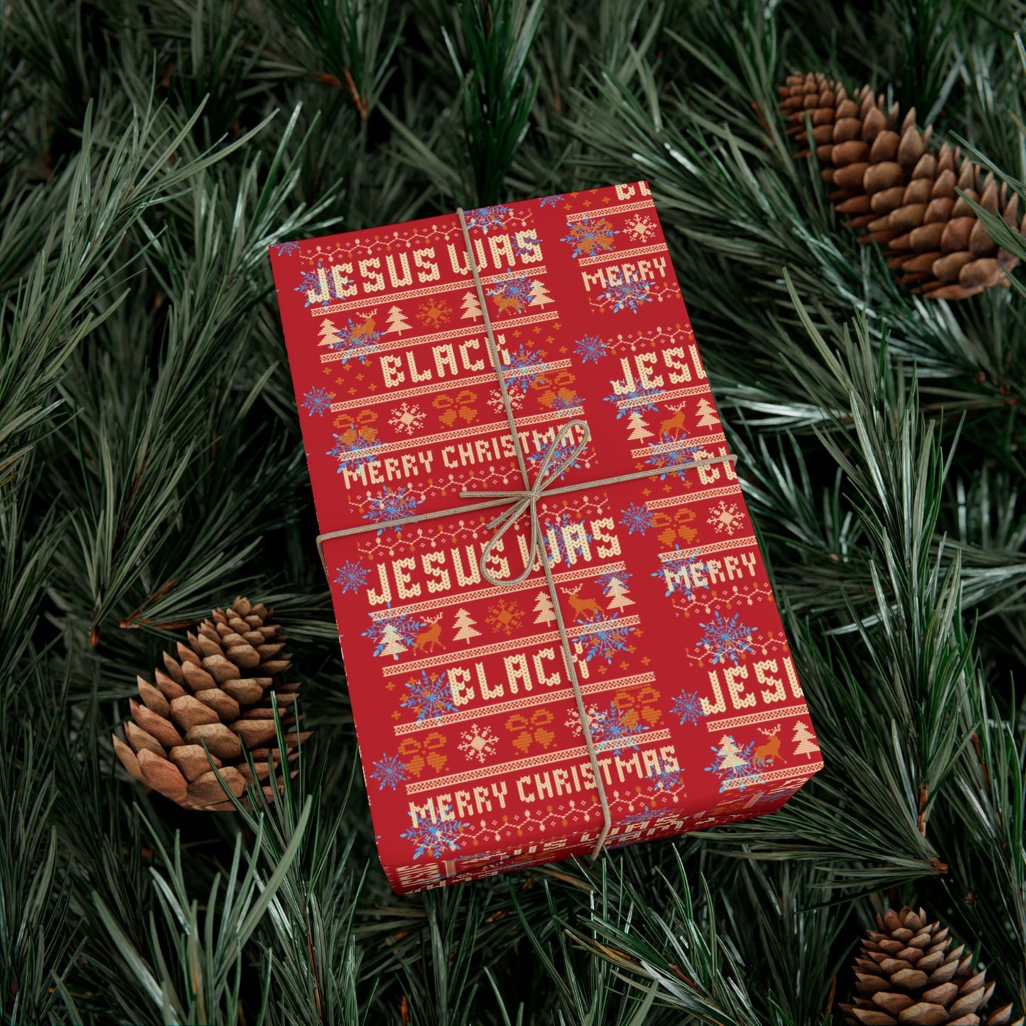 Christmas gift wrapped in Jesus Was Black Merry Christmas red paper surrounded by pinecones and greenery, bold and festive wrap.