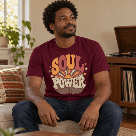 Man sitting on a couch beside a record player wearing the maroon Soul Power retro t-shirt