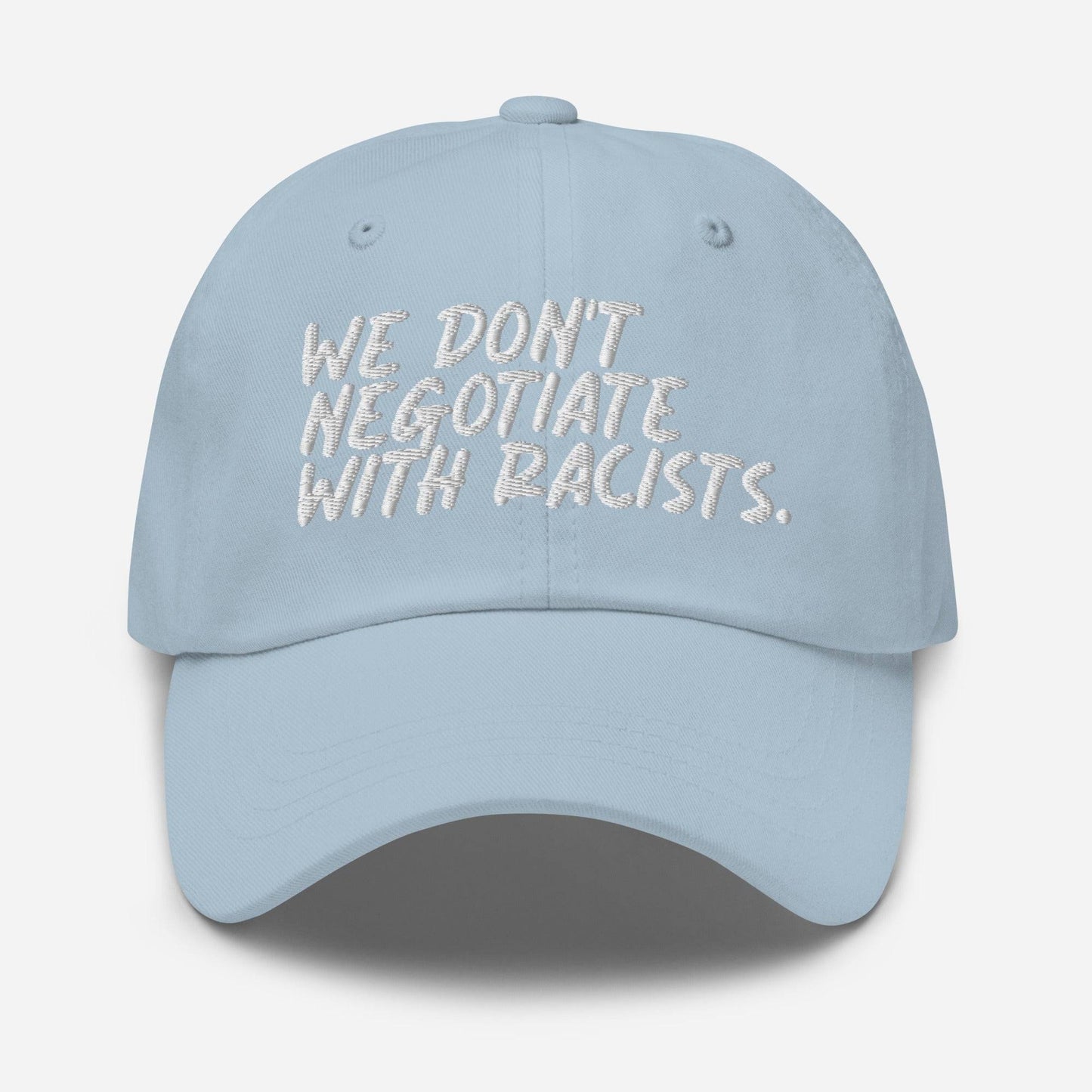 Light blue We Don't Negotiate With Racists Baseball Cap with white embroidered message. Soft-toned anti-racist cap with adjustable fit.