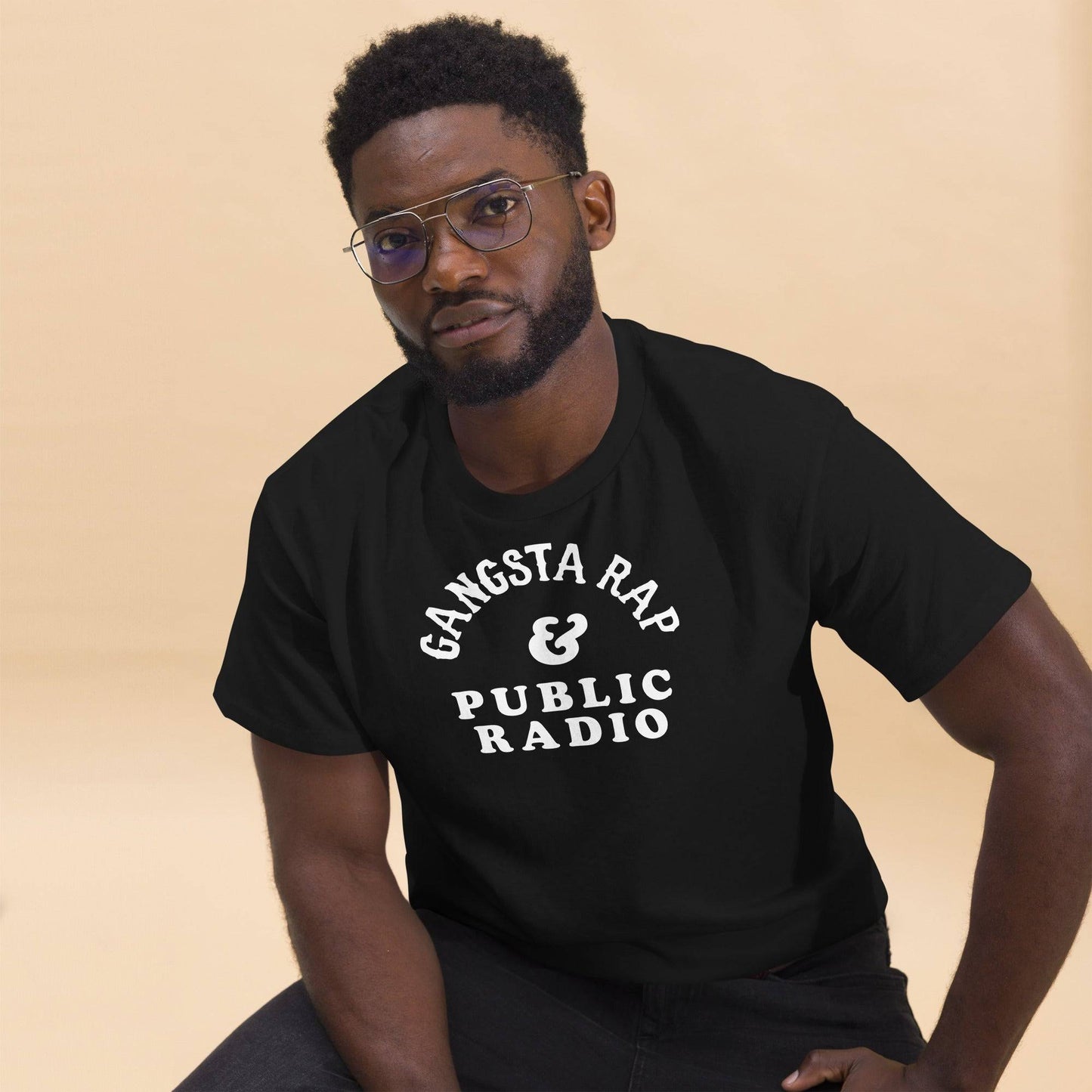 a man wearing a black t - shirt with the words gansta rap and public radio on it and glasses
