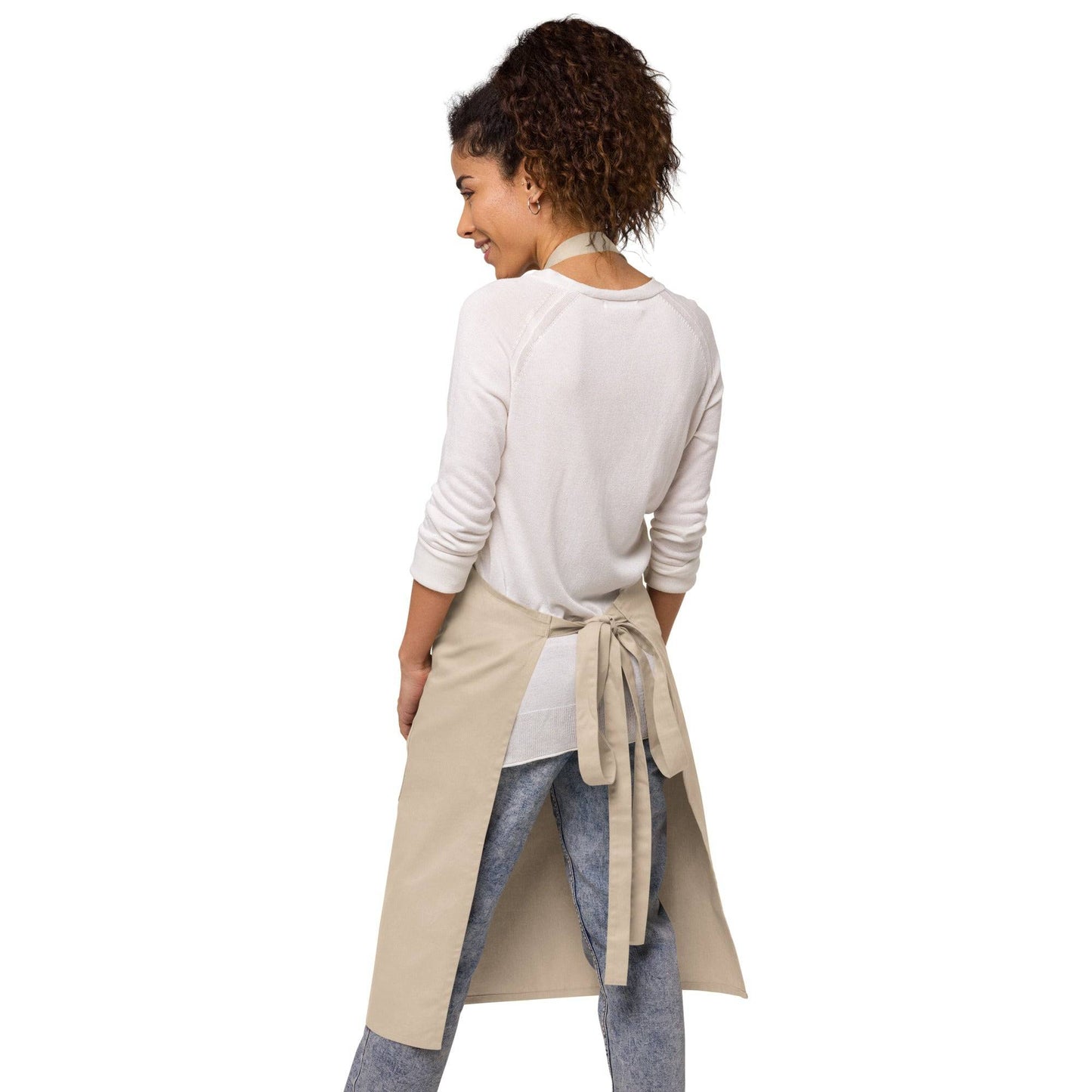 Back view of woman wearing BPP People's Free Food Program Organic Cotton Apron in beige, showcasing adjustable waist tie and relaxed fit.