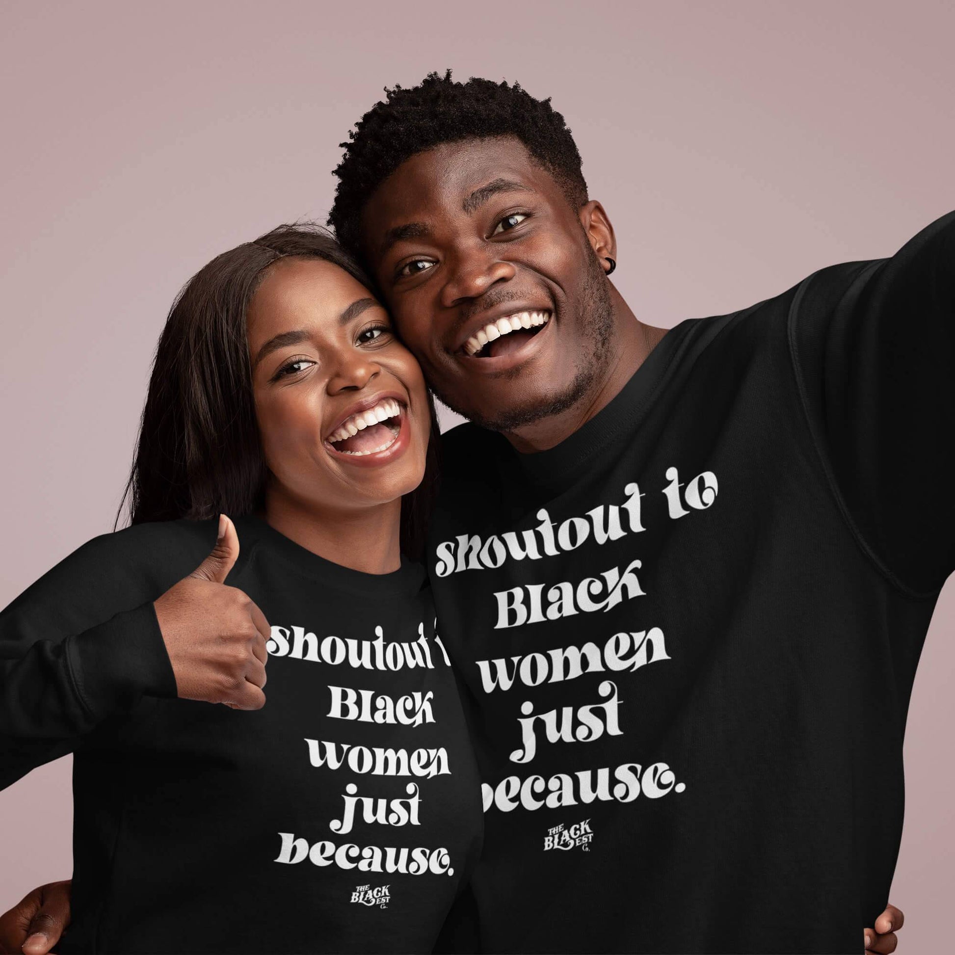 Smiling couple wearing matching 'Shoutout To Black Women Just Because' unisex sweatshirts, celebrating culture and unity in cozy style.