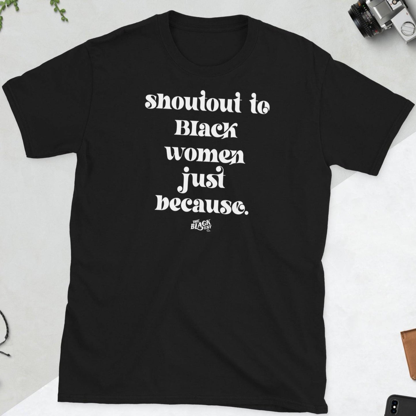 Black unisex t-shirt laid flat with bold white text reading 'Shoutout to Black Women Just Because.' A staple from the Shoutout To Black Women collection.
