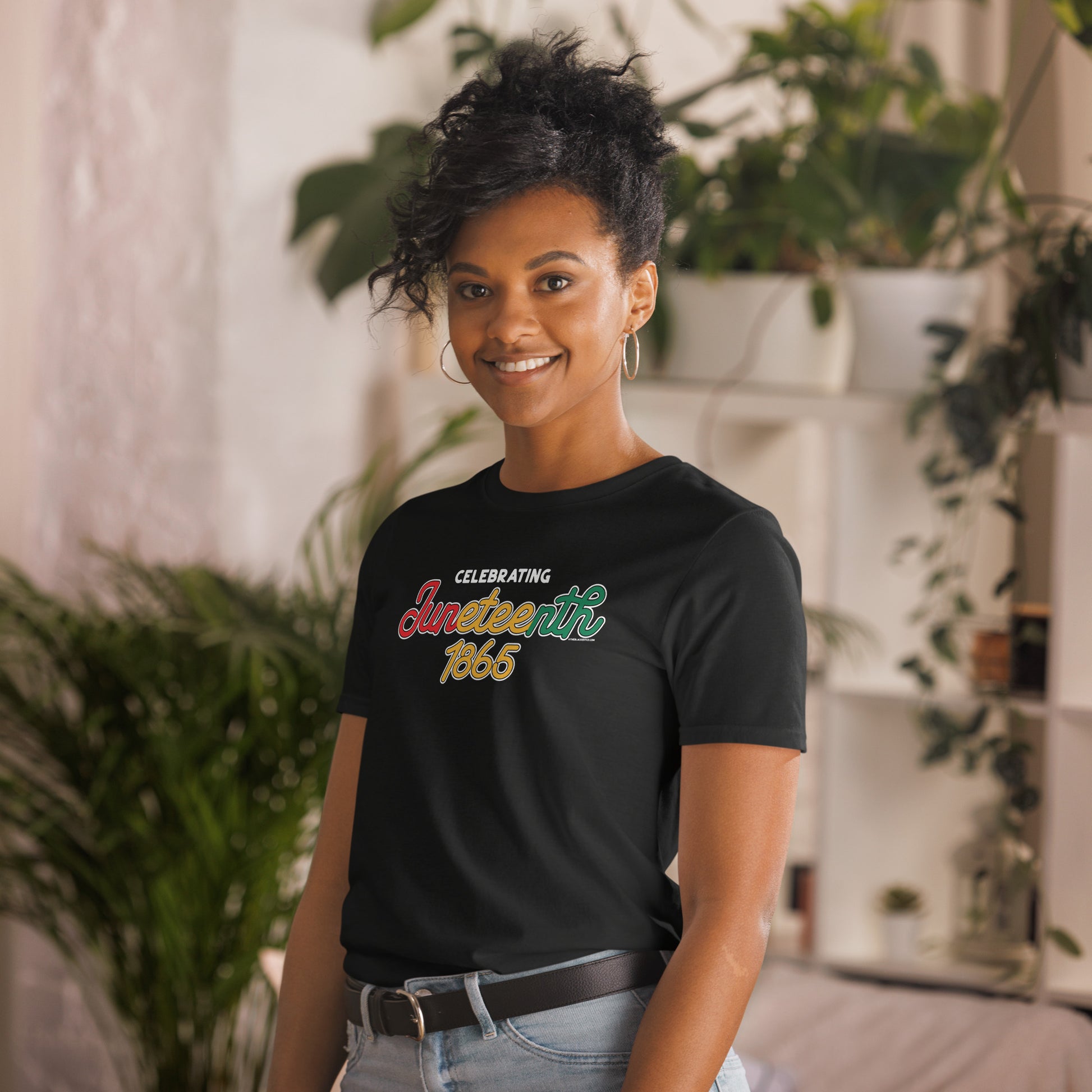 a woman standing in a room with a plant in the background in t - shirt with the words celebrating juneteenth 1865 on it