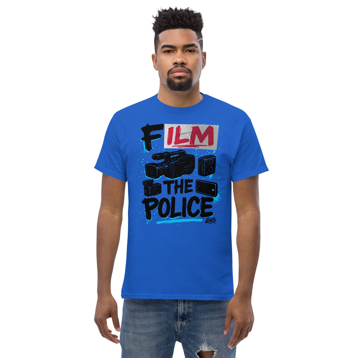 Man wearing blue Film The Police Staple T-shirt by TheBlackest Co., styled casually with jeans, showcasing bold protest design.