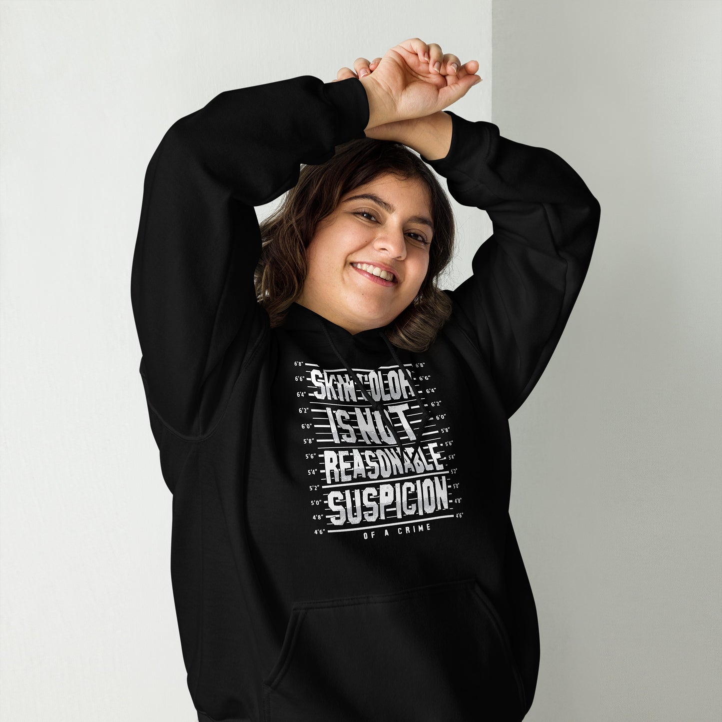Woman smiling in Skin Color Is Not A Crime Unisex Hoodie by TheBlackest Co., a soft black hoodie promoting anti-racial profiling awareness.