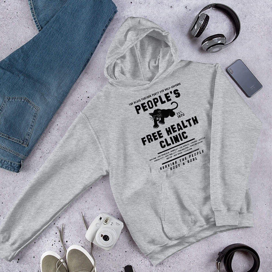 Gray People's Free Health Clinic BPP Unisex Pullover Hoodie with bold black text and graphic, styled flat with jeans, headphones, and accessories.