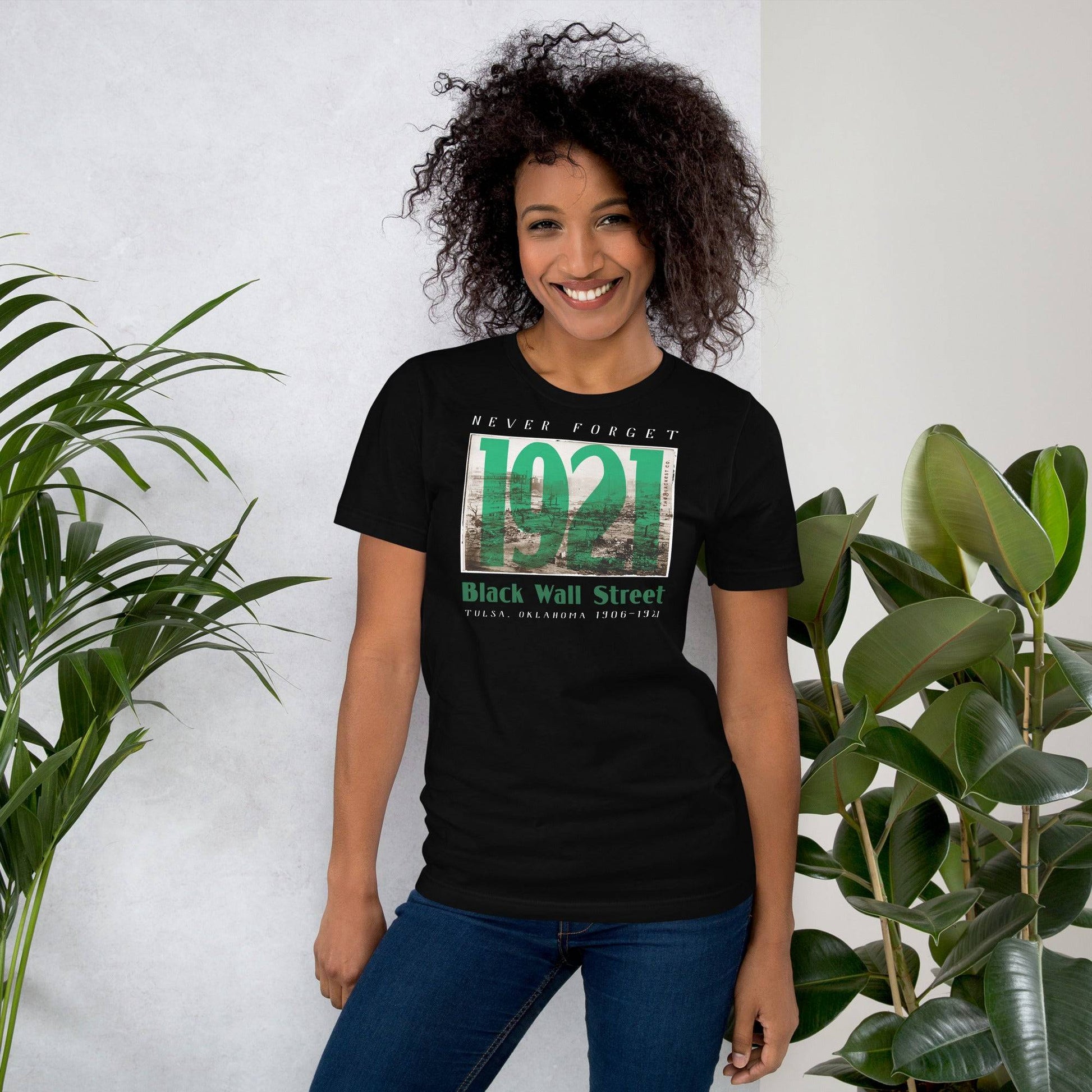 Woman in Black Wall Street 1921 t-shirt, standing by plants.