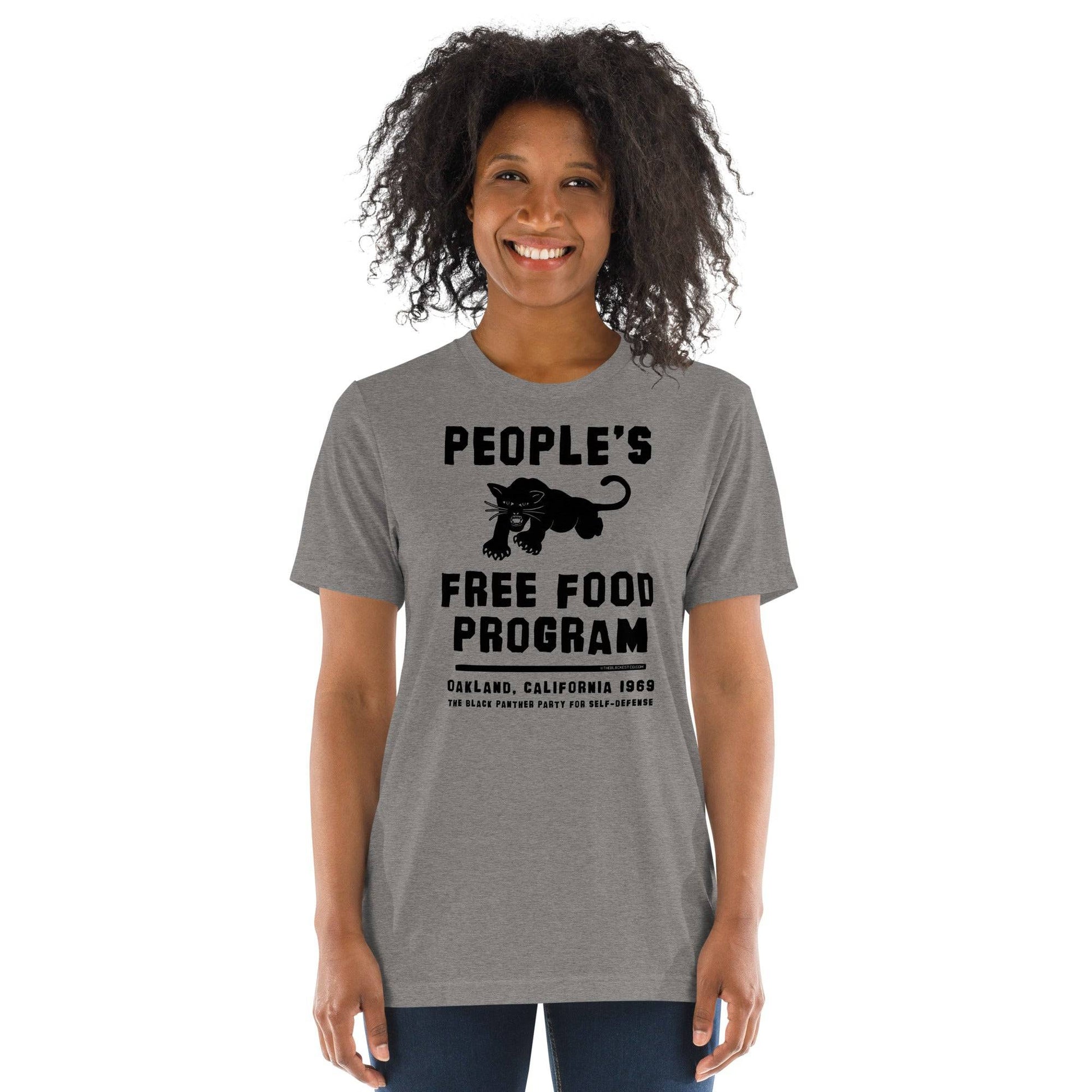 Woman wearing gray BPP People's Free Food Program Unisex Tri-Blend T-Shirt featuring retro black panther design and cultural tribute text.