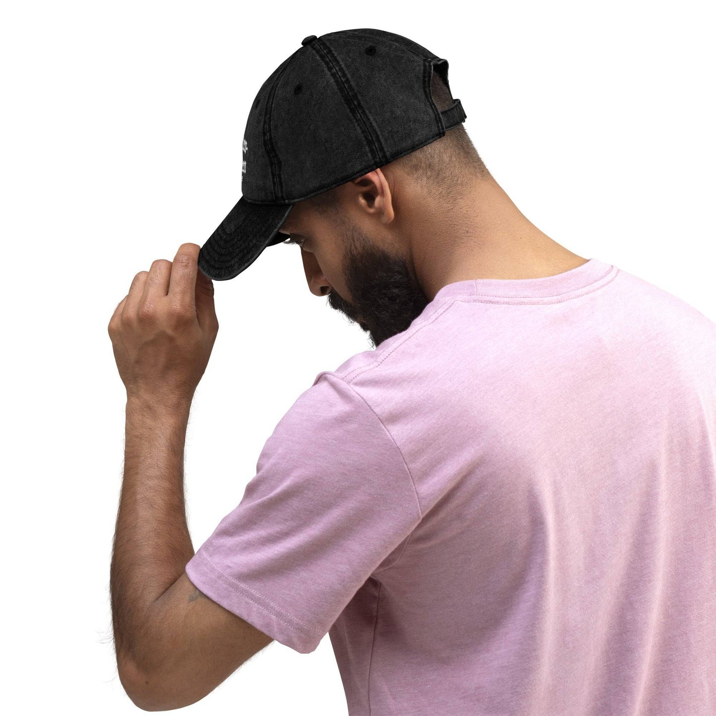 a man wearing a pink shirt and a black hat