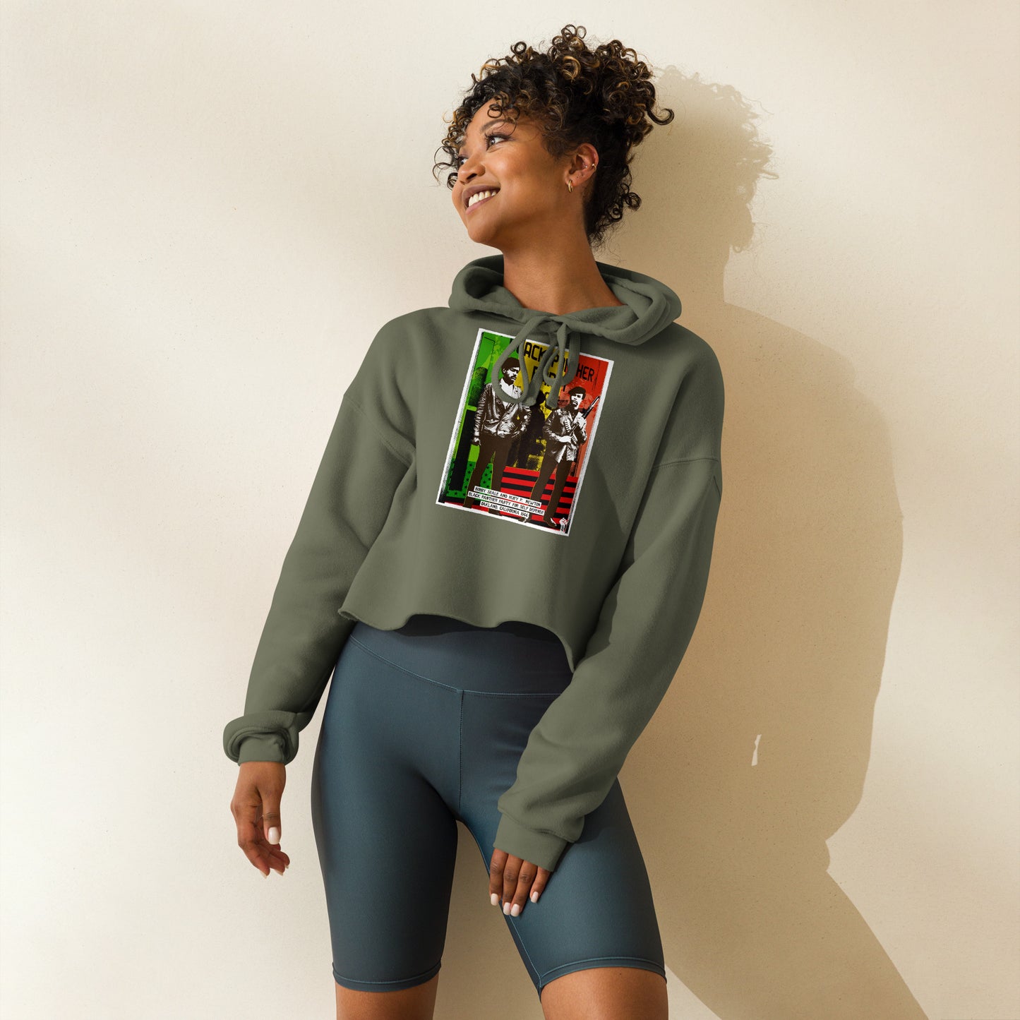 Woman posing in The Black Panther Party BPP Storefront Crop Hoodie paired with biker shorts, showcasing activewear versatility and cultural pride.