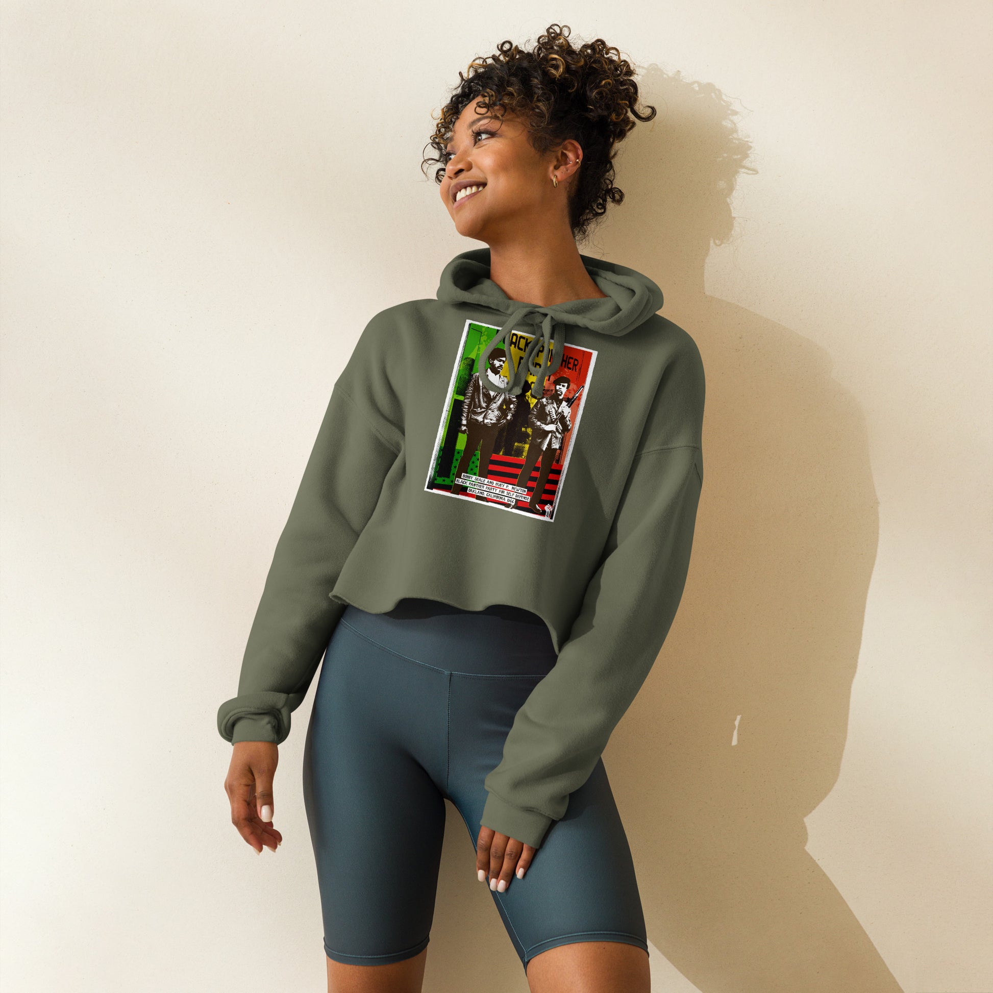 Woman posing in The Black Panther Party BPP Storefront Crop Hoodie paired with biker shorts, showcasing activewear versatility and cultural pride.