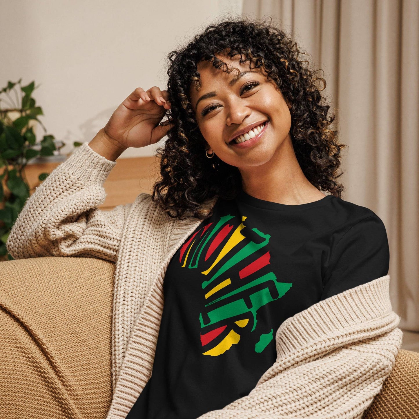 a woman sitting on a couch smiling at the camera in t - shirt with the word Mother in the shape of africa on it