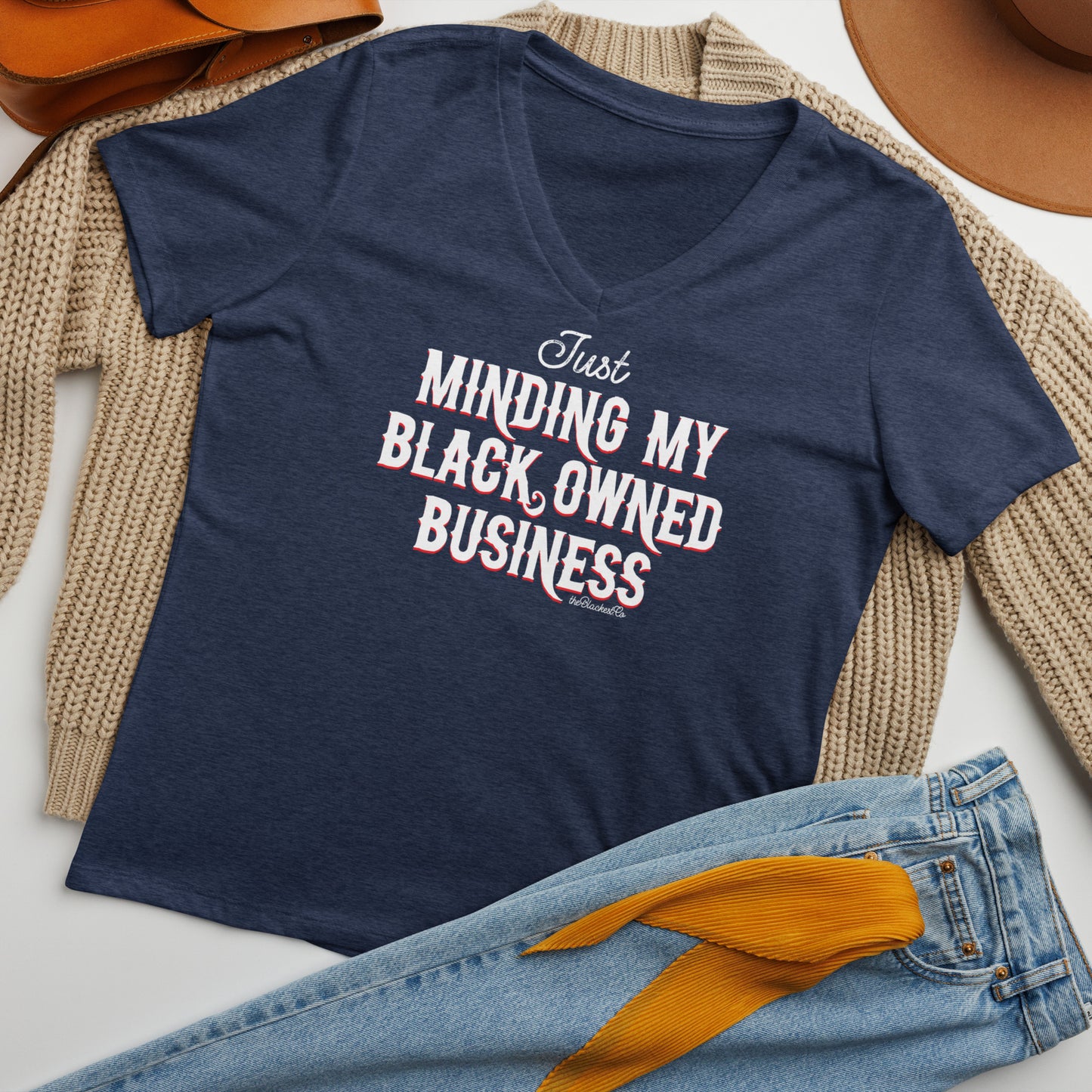 Flat lay of navy Minding My Black Owned Business Womens V-neck T-shirt styled with jeans and cardigan, casual fashion for women.
