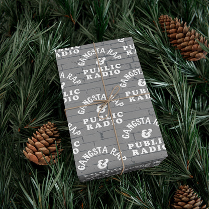 Gangsta Wrap & Public Radio Christmas Wrapping Paper on a gift nestled in pine branches, festive and urban-themed for holiday decor.