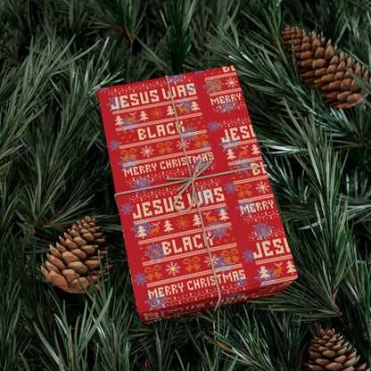 Gift wrapped in Jesus Was Black Merry Christmas red paper nestled in pine branches, festive and bold seasonal gift wrap design.
