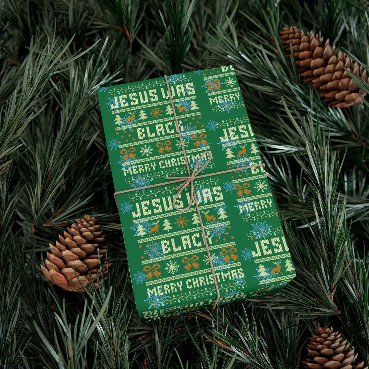 Gift wrapped in Jesus Was Black Merry Christmas green wrapping paper placed in pine branches, highlighting bold and cultural holiday celebration.