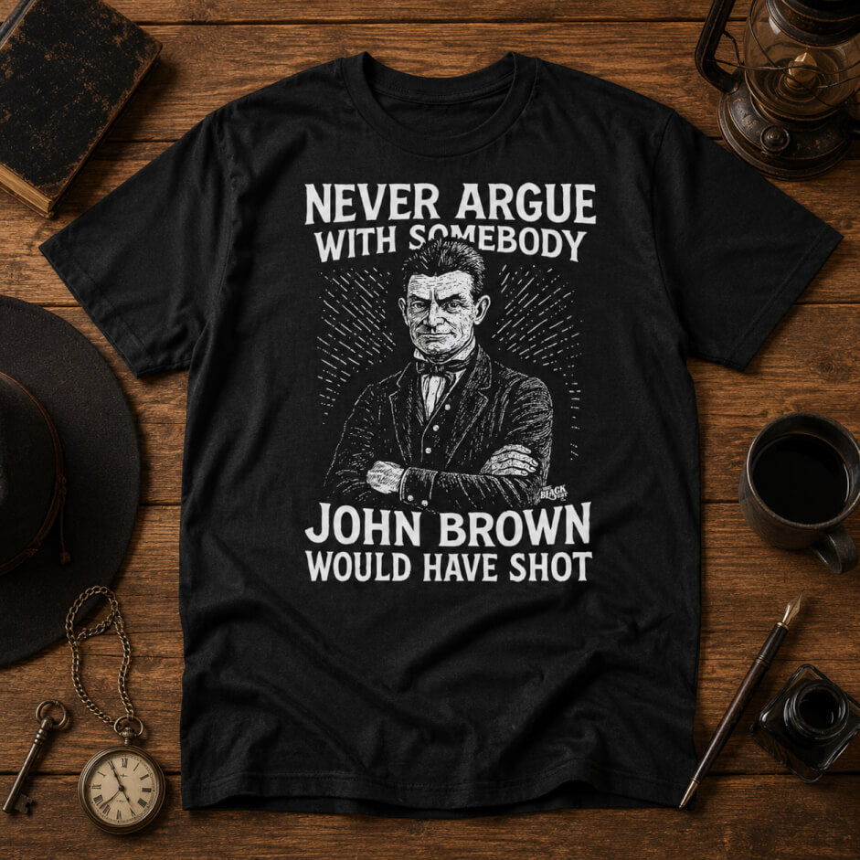 Black t-shirt with graphic of John Brown and text on a wooden surface with vintage items.