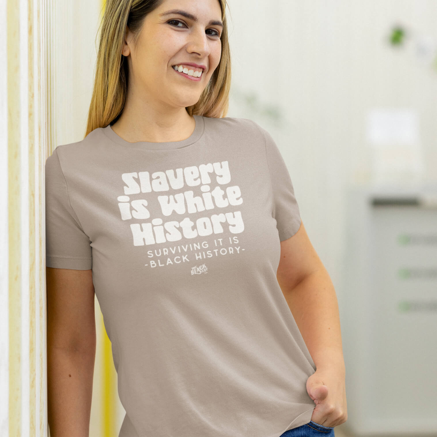 Smiling woman wearing the ALLEY VERSION Slavery Is White History women's relaxed t-shirt in sand color. A stylish statement piece for everyday wear.