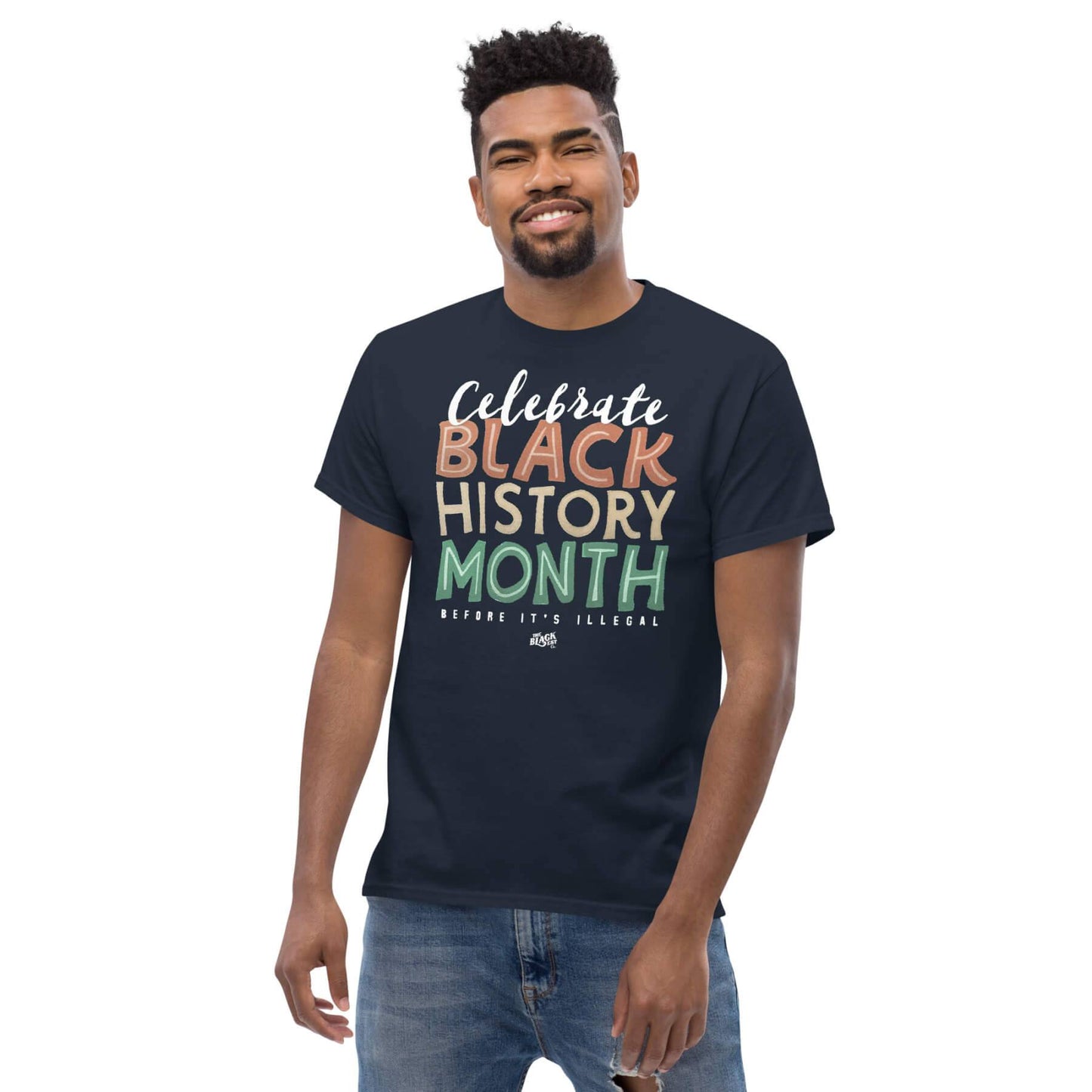 Man wearing a navy 'Celebrate Black History Month Before It's Illegal' t-shirt. Comfortable unisex graphic tee for Black History Month.