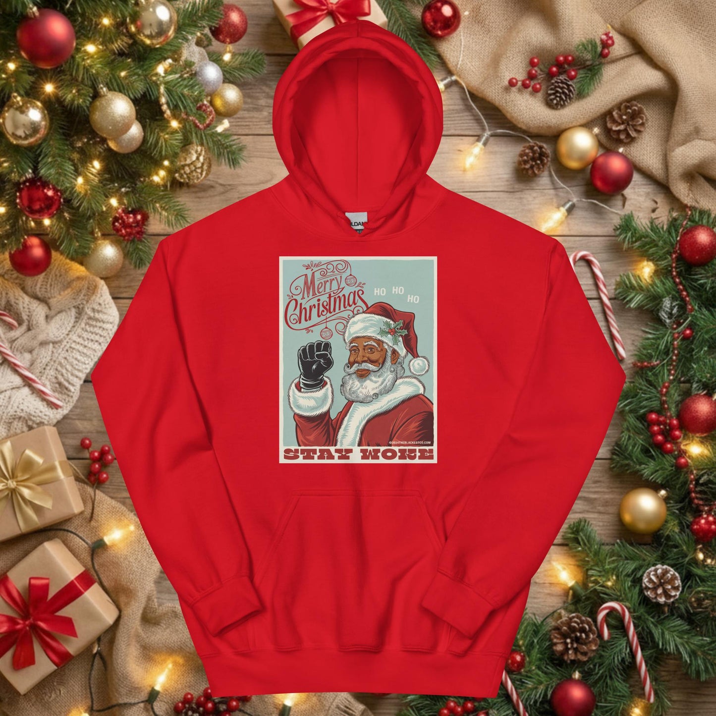 Red Black Santa Stay Woke Unisex Hoodie displayed flat under Christmas tree with gifts and ornaments, ideal for holiday gifting and cultural pride.