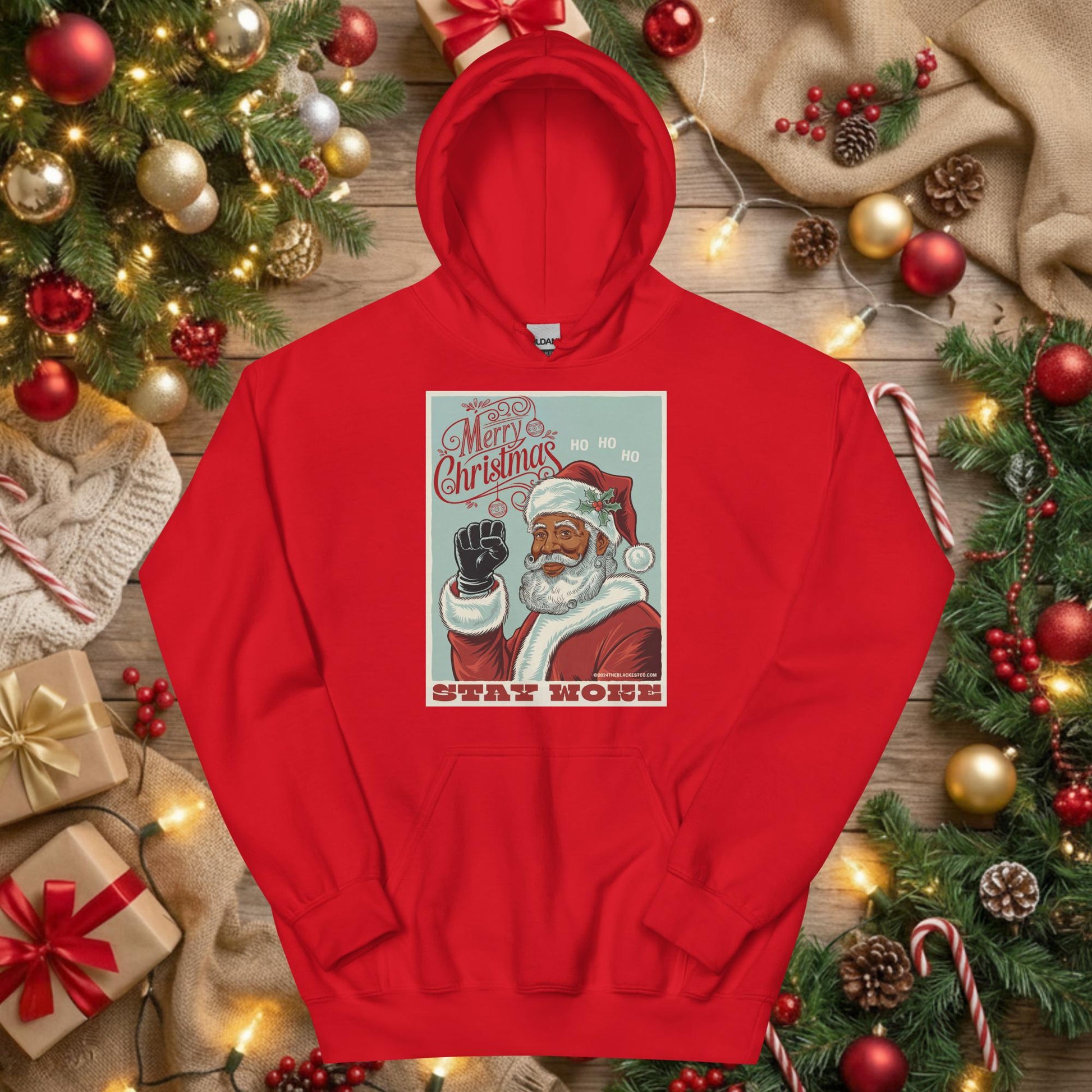 Red Black Santa Stay Woke Unisex Hoodie displayed flat under Christmas tree with gifts and ornaments, ideal for holiday gifting and cultural pride.