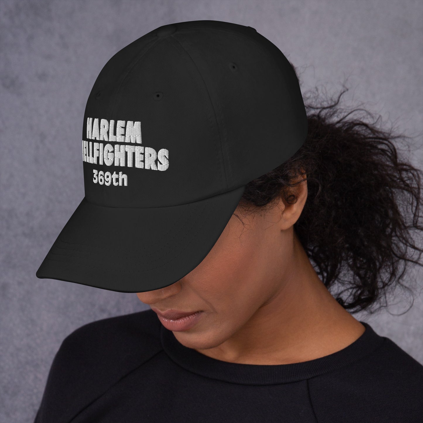 Woman wearing the black Harlem Hellfighters 369th baseball cap, showcasing its curved brim and embroidered front design. A stylish tribute to Black history.
