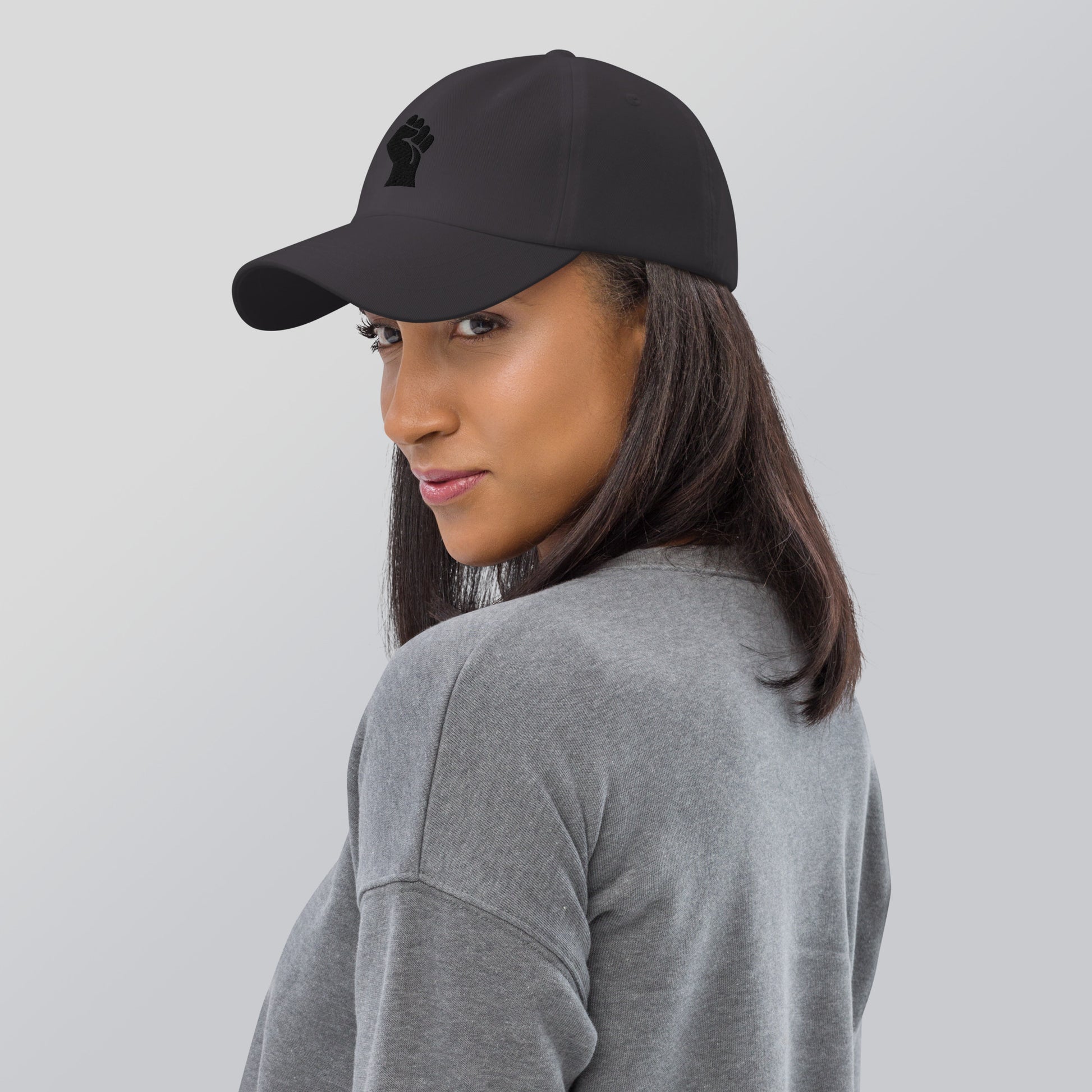 Model wearing Black On Black Power Fist Embroidered Baseball Cap, showcasing its sleek fit and bold black empowerment design.