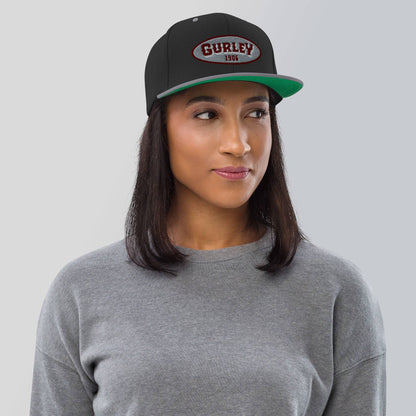 a woman wearing a grey shirt and a black and green hat