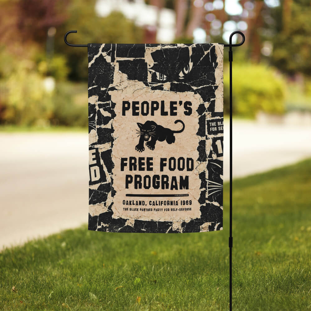 Black Panther Party Free Food Program garden flag on a stand in a front lawn along a sunny street