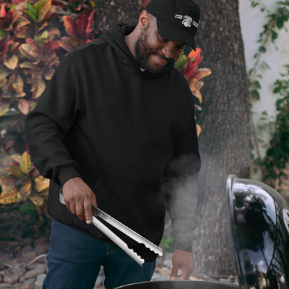 Man wearing the Double V Campaign Victory Home Abroad Baseball Cap while grilling outdoors, showcasing casual fit and cultural pride.
