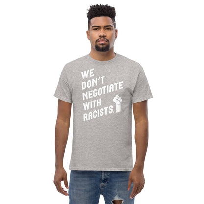man wearing a light gray t shirt with white lettering reading we don't negotiate with racists