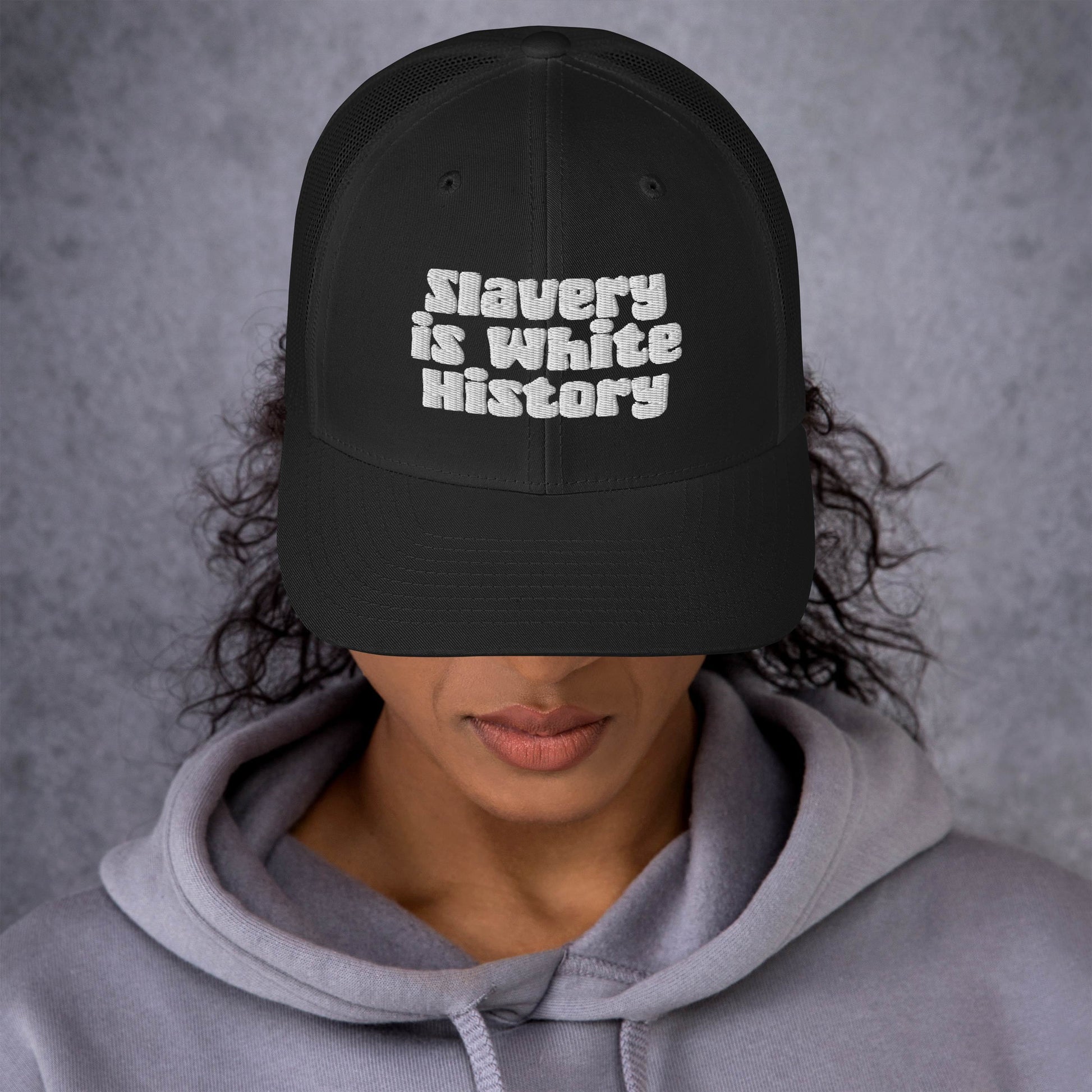 Woman wearing Slavery Is White History Trucker Hat by TheBlackest Co., showcasing bold embroidered message and structured front panel.