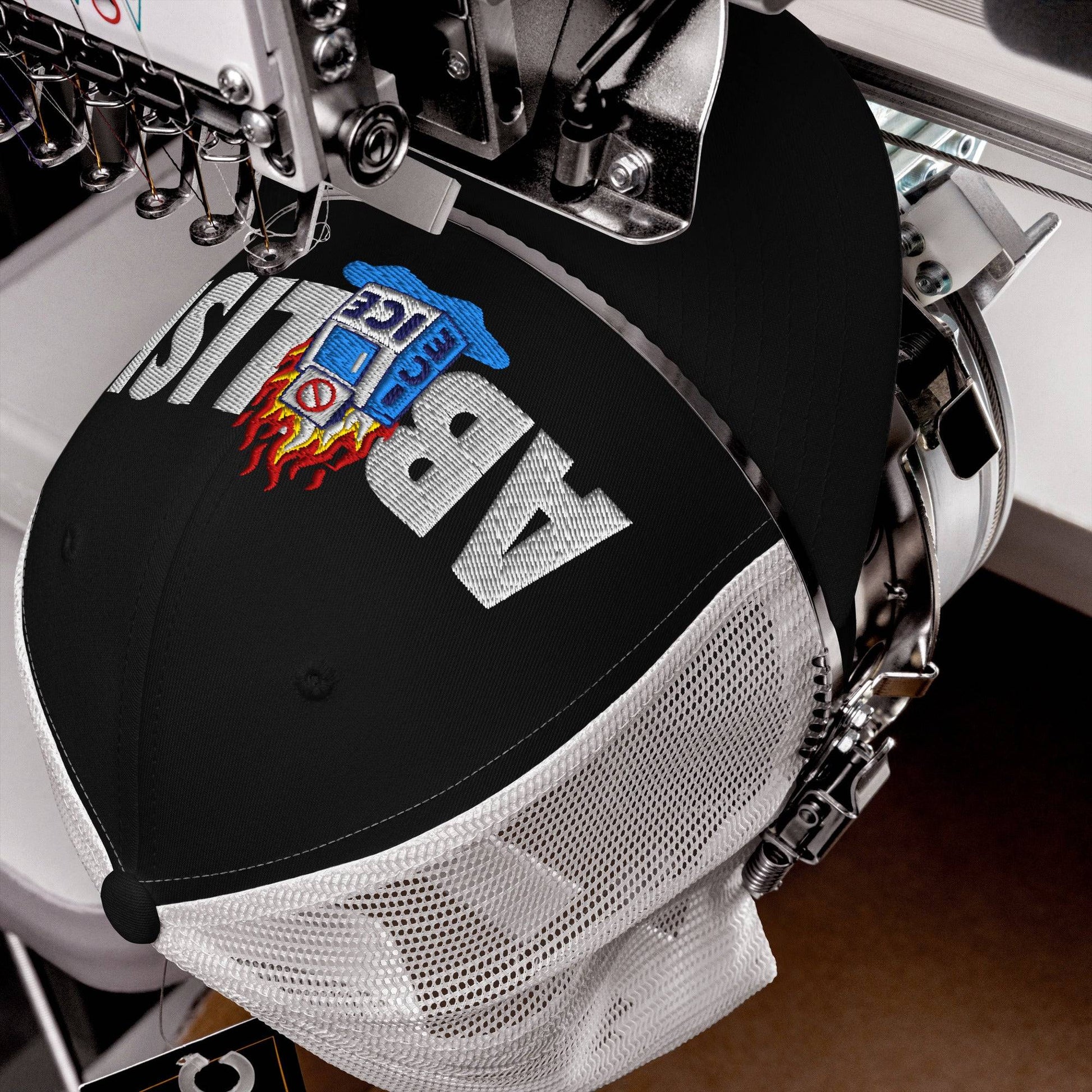 Close-up of ABOLISH Burning ICE Machine Trucker Hat by TheBlackest Co. being embroidered, highlighting detailed stitching and mesh structure.