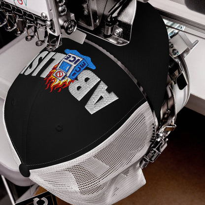 Close-up of ABOLISH Burning ICE Machine Trucker Hat by TheBlackest Co. being embroidered, highlighting detailed stitching and mesh structure.