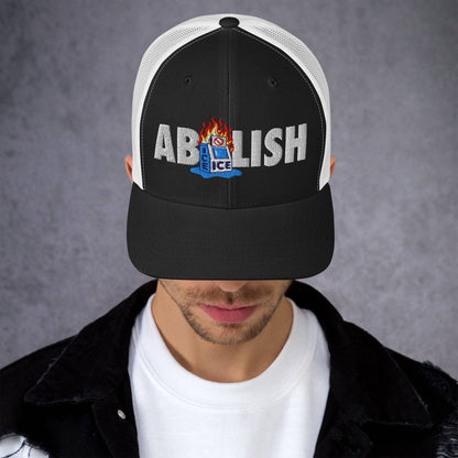 Black ABOLISH Burning ICE Machine Trucker Hat by TheBlackest Co. modeled by man, showcasing bold embroidery and mesh back panel.