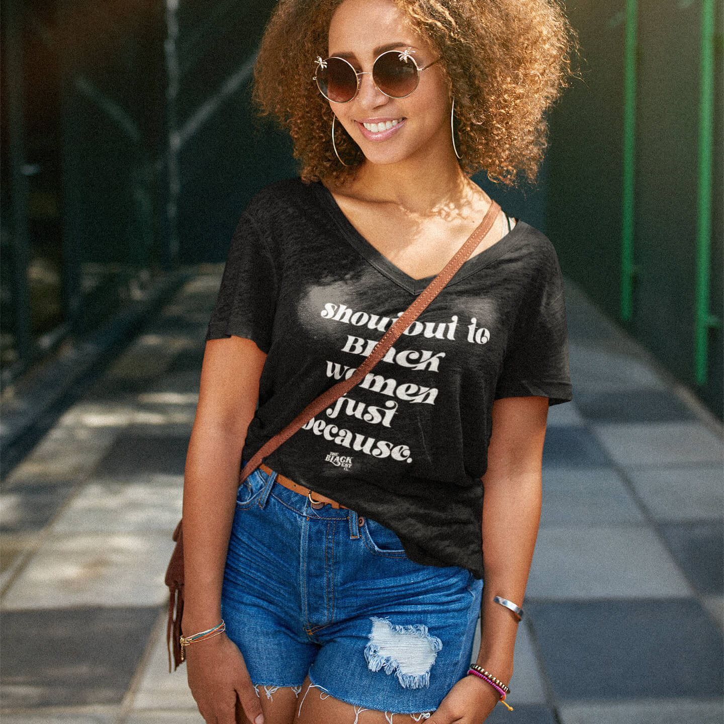 Woman wearing Shoutout To Black Women Just Because V-neck T-shirt styled with denim shorts, showcasing casual summer fashion for women.