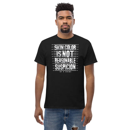 Model wearing a black unisex t-shirt with 'Skin Color Is Not Reasonable Suspicion of a Crime' text, promoting equality and social justice.