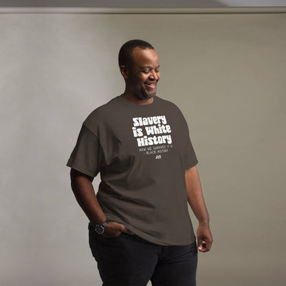 Man wearing a brown unisex t-shirt with the text 'Slavery Is White History, How We Survived It Is Black History,' smiling in a casual pose.