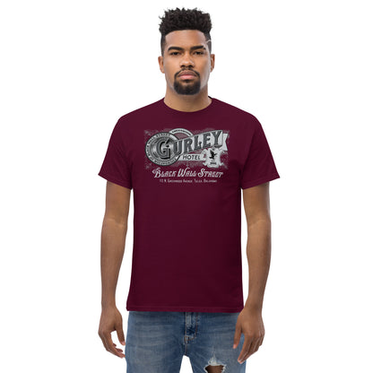 Model wearing burgundy Gurley Hotel graphic T-shirt with Black Wall Street design