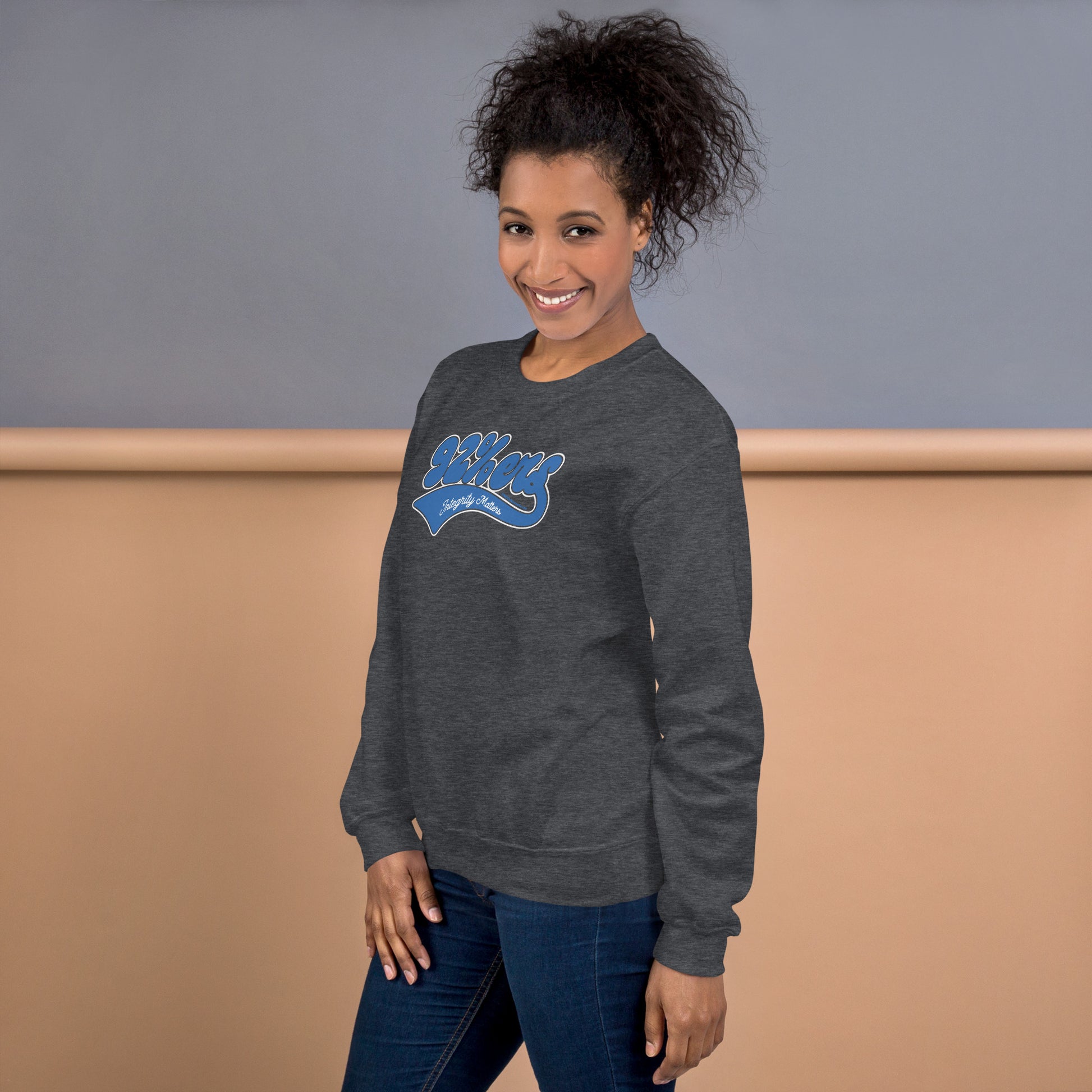 Woman smiling in the charcoal gray 92%ers Integrity Matters Sweatshirt by TheBlackest Co., paired with jeans. Perfect for casual, cozy looks.