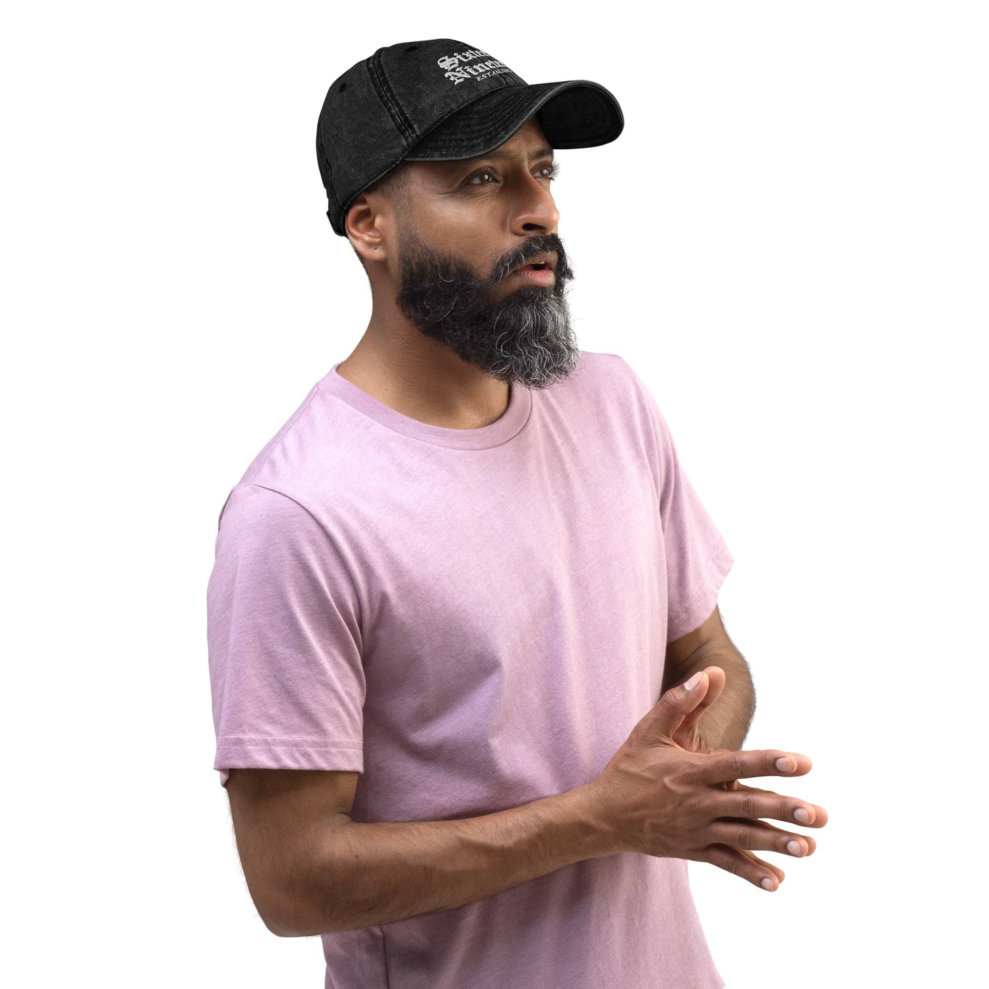 a man with a beard wearing a pink shirt and a black hat