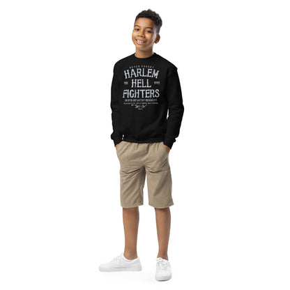 Full-body view of a boy wearing a black 'Harlem Hellfighters' crewneck sweatshirt and beige shorts, styled for a relaxed, youthful look.