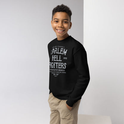 Smiling boy wearing a black 'Harlem Hellfighters' crewneck sweatshirt paired with beige shorts, showcasing a casual and comfortable fit.