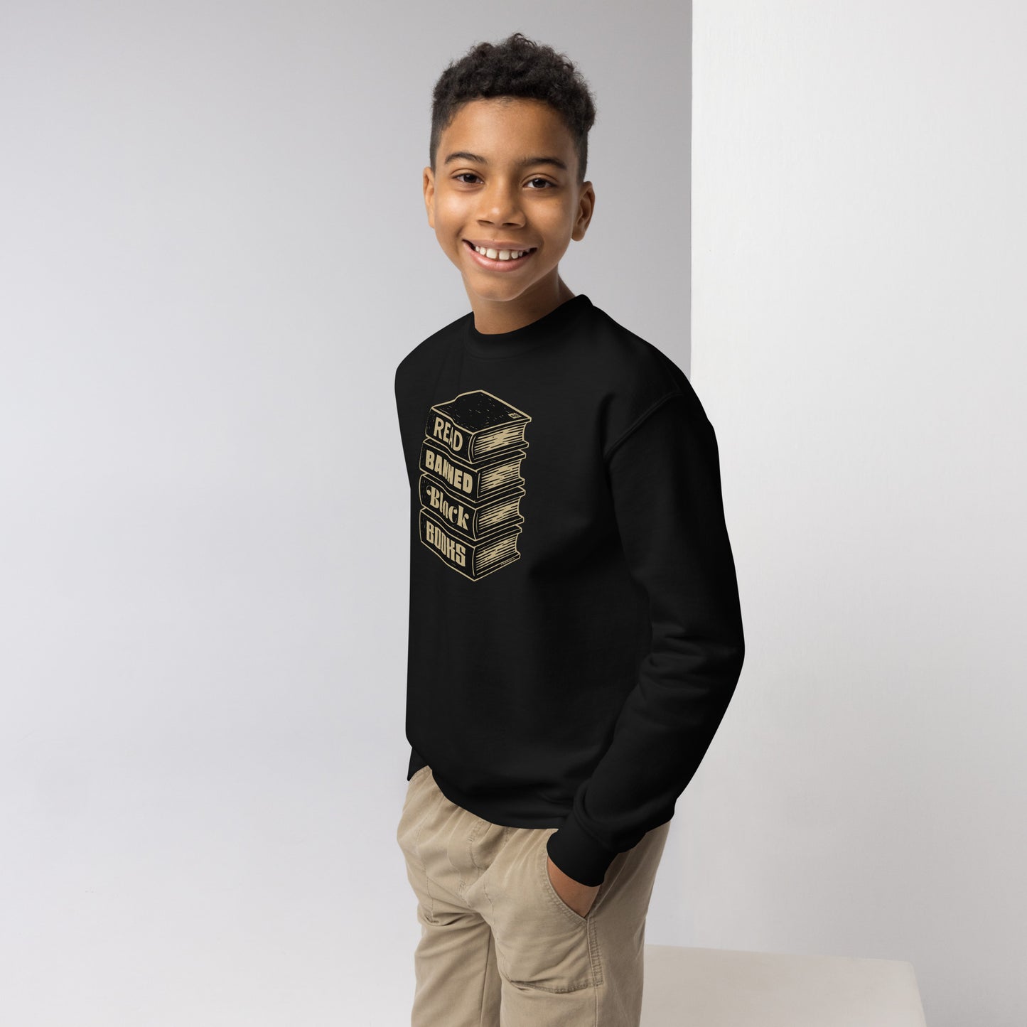 Smiling boy wearing YOUTH Read Banned Black Books Crewneck Sweatshirt by TheBlackest Co., ideal for educational and literacy pride apparel.