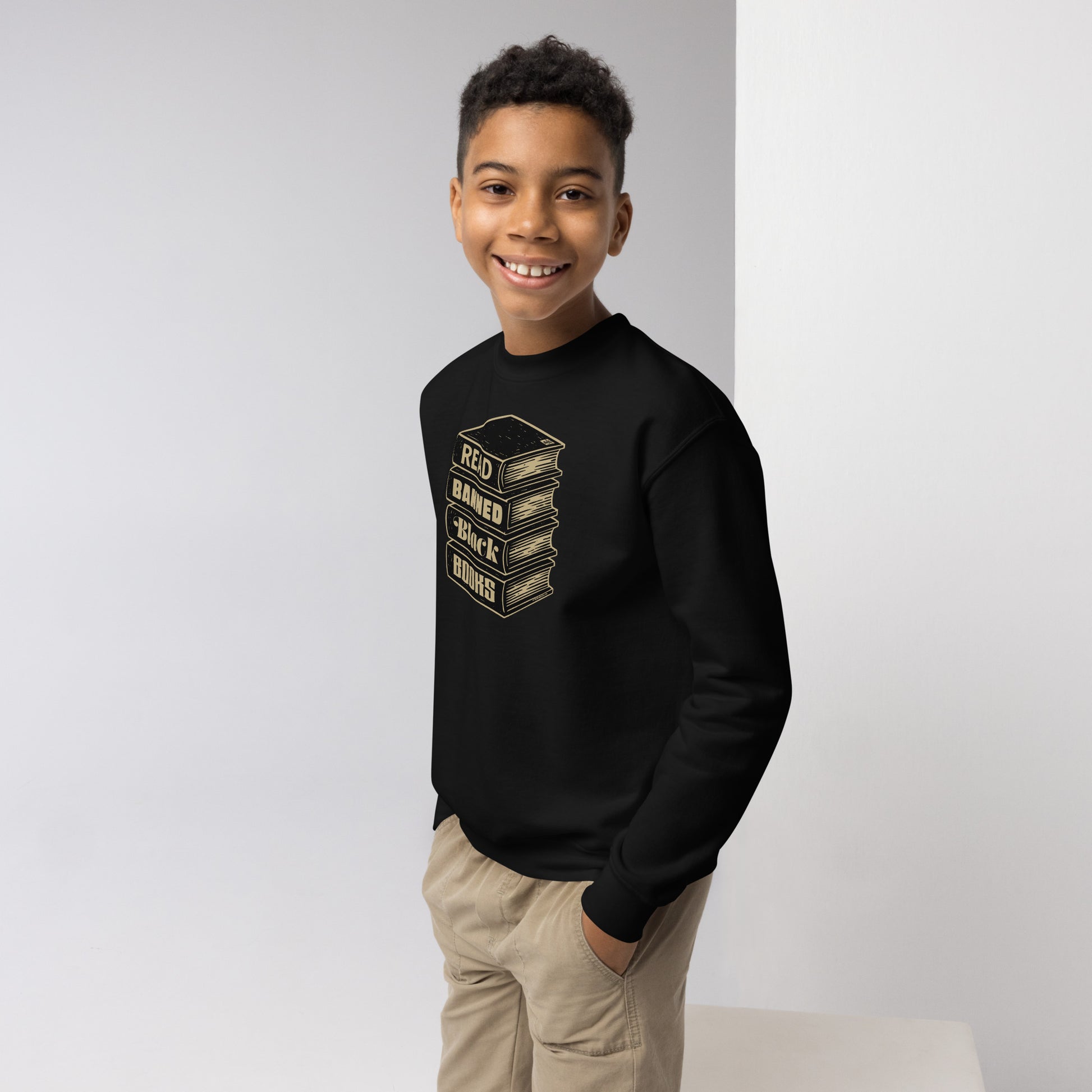 Smiling boy wearing YOUTH Read Banned Black Books Crewneck Sweatshirt by TheBlackest Co., ideal for educational and literacy pride apparel.